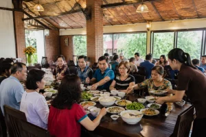 Đoàn khách du lịch dừng chân dùng bữa tại một nhà hàng ở Gia Nghĩa, không gian rộng rãi với nhiều bàn ăn và nhân viên phục vụ trong bối cảnh Việt Nam