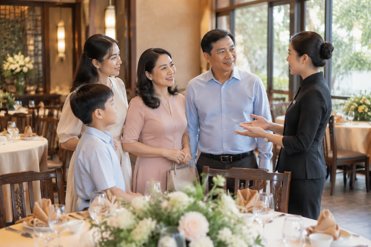 Gia đình Việt Nam cùng nhân viên nhà hàng trao đổi các bước chuẩn bị cho một buổi tiệc trong không gian sảnh riêng, thể hiện sự phối hợp và thống nhất kế hoạch trước ngày tổ chức.